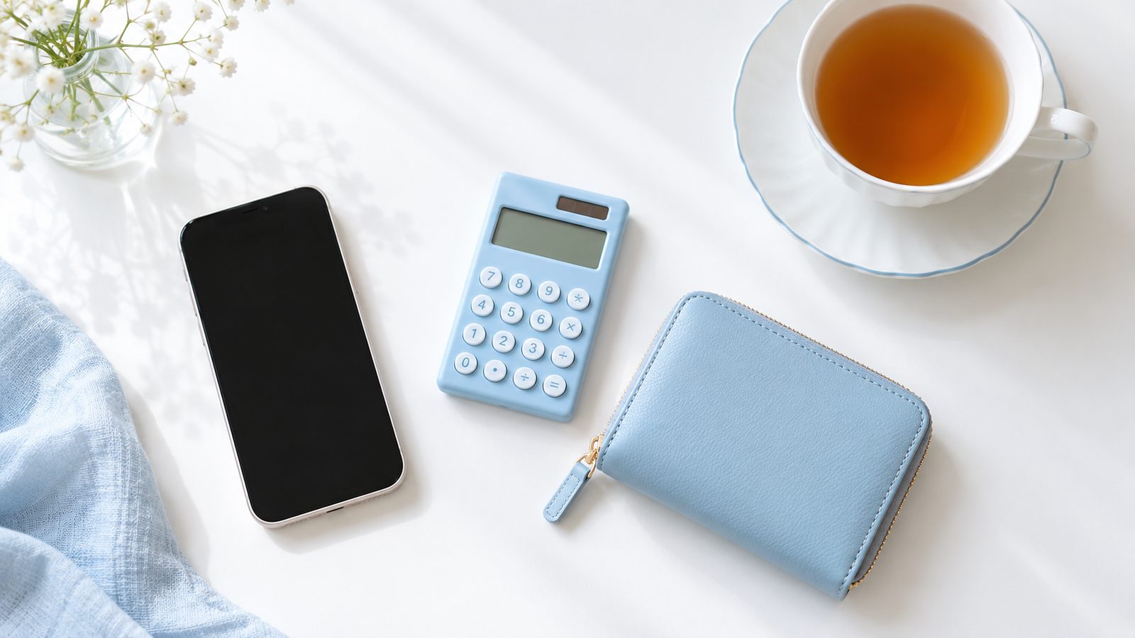 机の上に並んだスマホと電卓と財布と紅茶